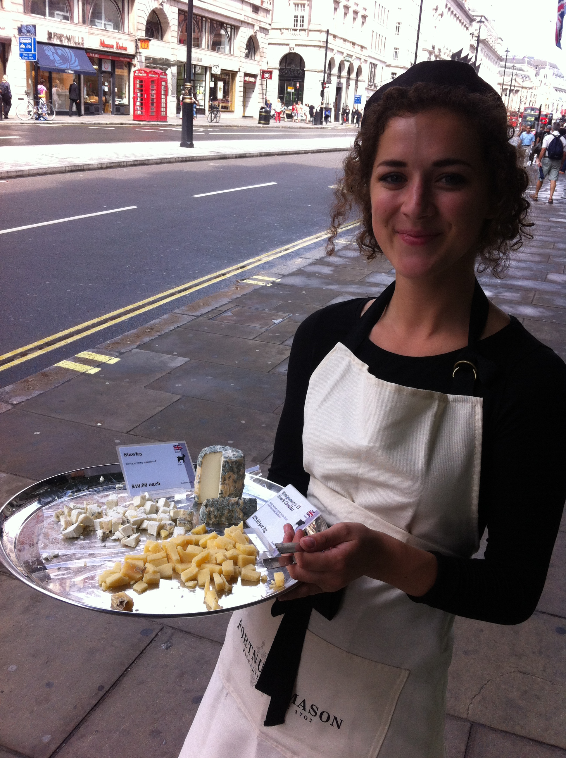 A young lady gives away cheese on the street